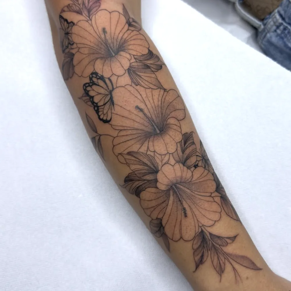 Tatuaje botánico de hibiscos y mariposa en el antebrazo, línea fina, Madrid
